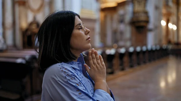 Young beautiful hispanic woman praying at St. Karl Borromus church
