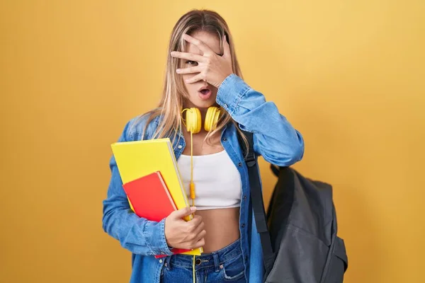 Young Blonde Woman Wearing Student Backpack Holding Books Peeking Shock — Stock Photo, Image