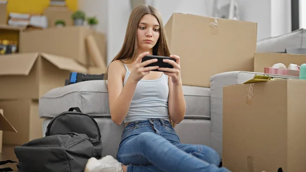 新しい家で床に座ってビデオゲームをしている若い美しい女の子 — ストック写真