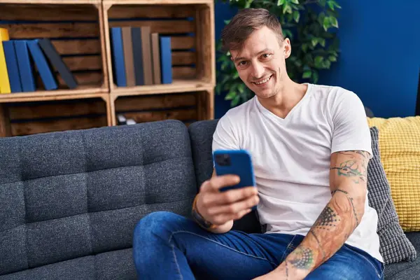 Genç adam evde koltukta oturan smartphone kullanarak