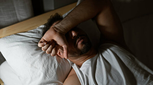 Молодой араб лежит на кровати и спит в спальне.