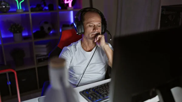 ハンサムな中年男性は夜にビデオゲームをストリーミングし 未来的な技術を完備した彼のサイバーゲームルームに真剣に集中しています — ストック写真