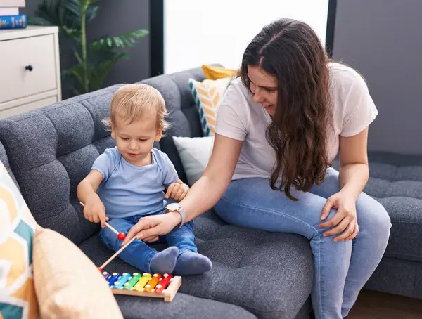 stock image Mother and son sitting on sofa playing xylophone at home