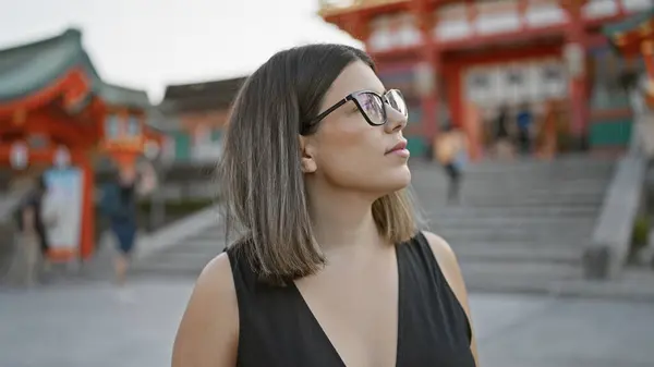 メガネをかけた美しいヒスパニック系女性 明らかに京都の素晴らしい寺院の周囲に魅了された笑顔でポーズ — ストック写真