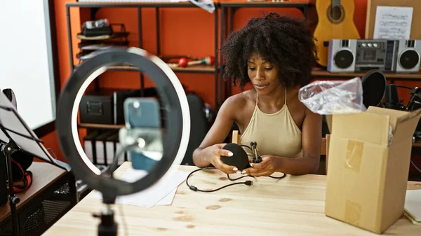 African american woman radio reporter recording video unpacking microphone of cardboard box at radio studio