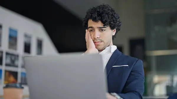 Young latin man business worker using laptop stressed at office