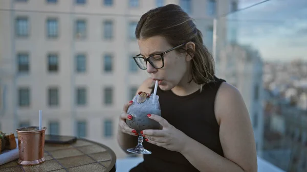 美しいヒスパニックの女性 メガネを寄付し 屋上テラスで熱帯カクテルを貯蓄し 街の上に泡立って祝う — ストック写真