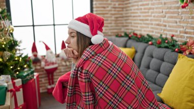 Beyaz kadın battaniyeyle örtülmüş evde üzgün bir ifadeyle Noel 'i kutluyor.