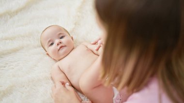 Anne ve kızının kapalı mekanda bağ kurması, aile yatak odalarının rahatlığında yatakta birlikte oynamaları, sevgi dolu yaşam tarzlarının bir ifadesi.