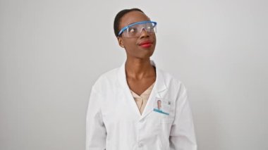 Heyecanlı Afrikalı Amerikalı kadın bilim adamı, üniformalı, parlak fikirli! Tek parmakla işaret ediyor, neşeli bir yüz sade beyaz bir arka planı aydınlatıyor..