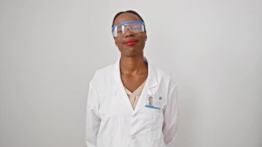 Neşeli Afro-Amerikan kadın bilim adamı üniformalı, kendinden emin bir şekilde kendine sarılıyor, beyaz izole edilmiş arka planda gülümsüyor..