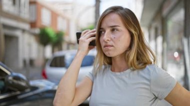 Parlak sarışın kadın, şehrin sokaklarında dolaşırken akıllı telefonuyla bir sesli mesaj gönderiyor.