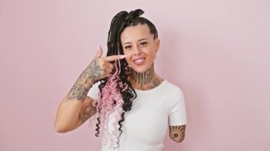 Göz alıcı İspanyol ampüte kadın, burnunu işaret eden parmak, izole edilmiş pembe arka plan, somutlaşmış güzellik ve güç.