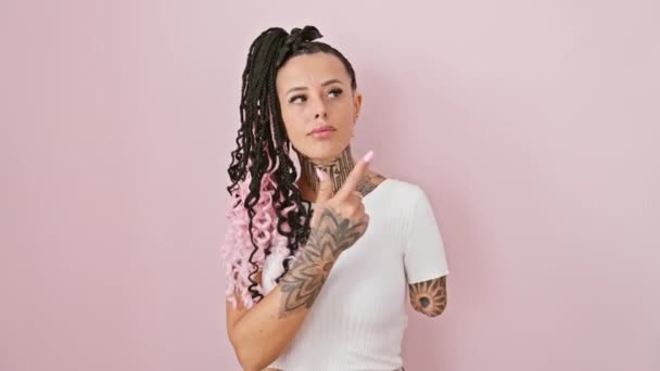 バラ色のピンクの孤立した背景に立ってTシャツのヒスパニックアンプティーの女性に自信を持って 彼女は真面目な顔をして 広告を披露している — ストック動画