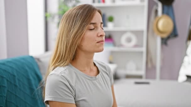 Atractiva Mujer Rubia Joven Meditando Mientras Sienta Tranquilamente Sofá Casa — Vídeos de Stock