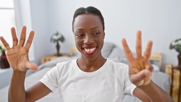 아늑한 침실에 누워있는 쾌활한 아프리카계 미국인 행복하게 빛나는 미소로 손가락을 — 비디오