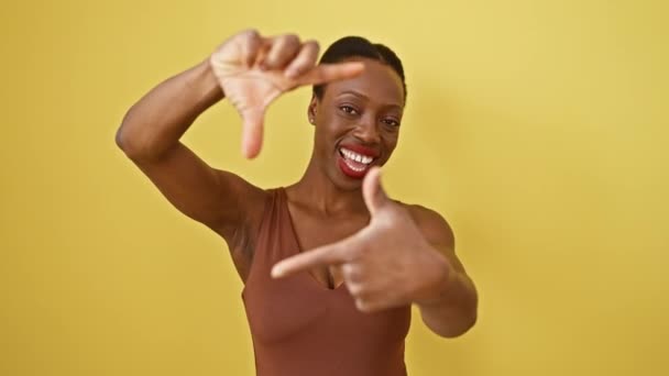 笑顔のアフリカ系アメリカ人女性は 黄色い隔離された背景に手で折られた写真のジェスチャーを作ります — ストック動画