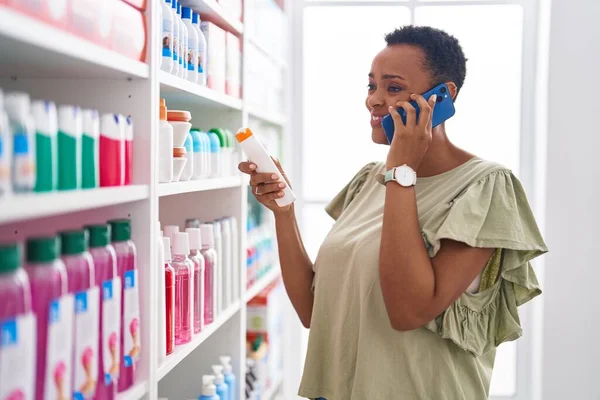 African american woman customer smiling confident talking on smartphone at pharmacy