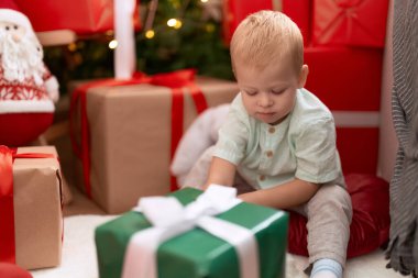 Sevimli çocuk evde Noel hediyeleriyle yerde oturuyor.