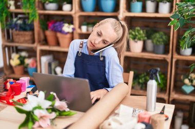 Çiçekçide dizüstü bilgisayarla konuşan sarışın bir çiçekçi.