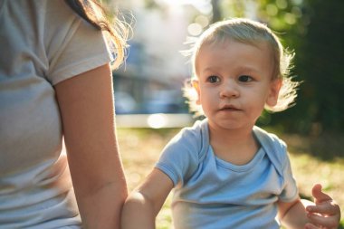 Anne ve oğlu parkta rahat bir ifadeyle bankta oturuyor.