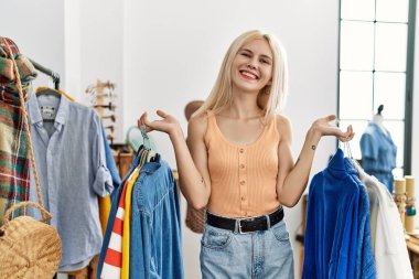 Elbise mağazasında gülümseyen genç sarışın kadın müşteri.