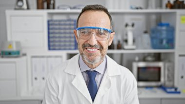 Beyaz saçlı, kendinden emin orta yaşlı bir adam. Laboratuvarda çalışırken sevinçle gülümseyen. Elementindeki mutlu bilim adamını somutlaştırıyor..