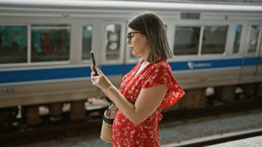 Gözlüklü güzel İspanyol kadın, tren yolculuğunu telefon kulübesinde kaydediyor. Şehir içi hayat tarzını yaşıyor..