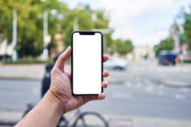 Elinde akıllı telefon tutan adam sokakta beyaz beyaz ekran gösteriyor