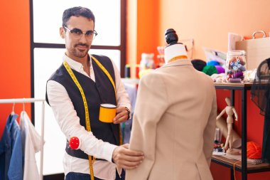 Genç İspanyol terzi atölyede manikinin yanında kahve içiyor.