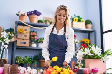 Young blonde woman florist make bouquet of flowers at florist