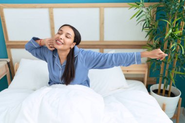 Genç Arap kadın yatak odasında kollarını esneterek uyanıyor.
