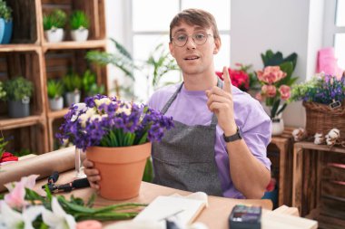 Çiçekçide çalışan beyaz, sarışın bir adam başarılı bir fikri işaret ediyor. Heyecanlı ve mutlu. Bir numara.. 