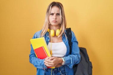 Sırt çantası takan, elinde kitap tutan, kuşkucu ve gergin genç sarışın bir kadın sorun yüzünden üzgün. negatif kişi. 