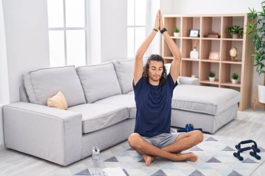 Young hispanic man training yoga at home