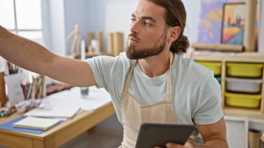 Young hispanic man artist using touchpad drawing at art studio