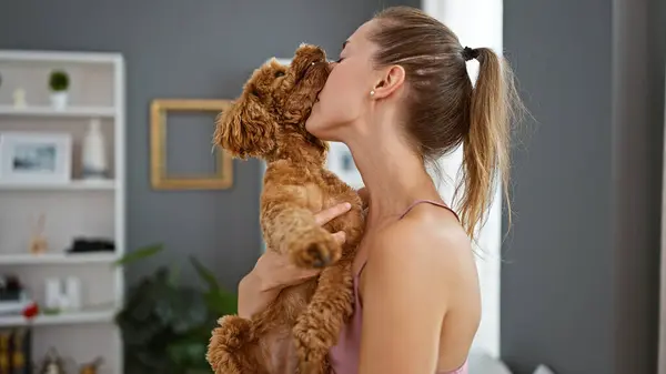 Young caucasian woman with dog kissing at home