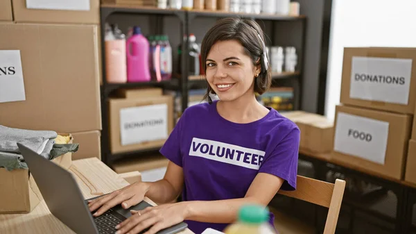 Portrait of a smiling young hispanic woman with short hair, beautiful volunteer working online in call center at charity, laptop, headphones on