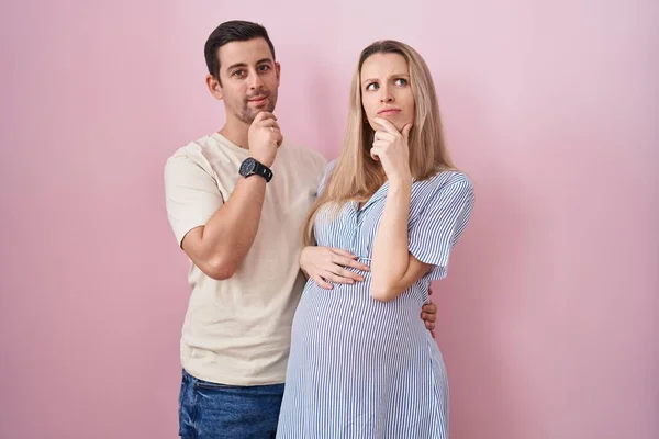 Young Couple Expecting Baby Standing Pink Background Looking Confident Camera — Stock Photo, Image