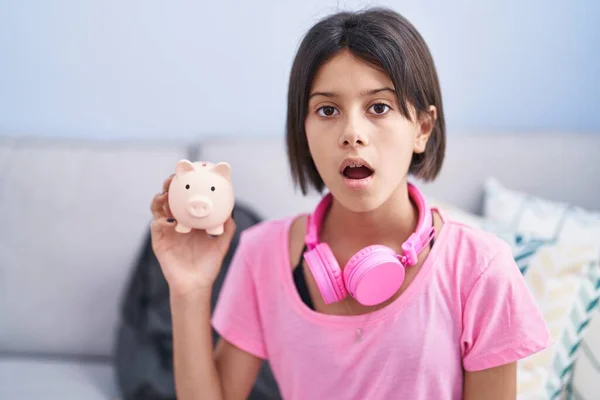 Young Girl Holding Piggy Bank Scared Amazed Open Mouth Surprise — Stock Photo, Image