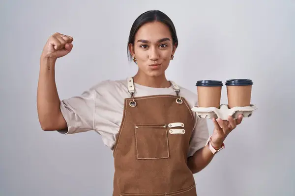 年轻的惊慌失措的女人穿着专业女服务员围裙 手里拿着咖啡 强壮有力 显示出臂膀肌肉 自信而自豪 — 图库照片