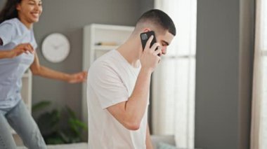 Güzel bir çift, evde canlı sohbetin tadını çıkarıyor. Kız arkadaşını sırtında tutan adam, akıllı telefonda mutlu bir şekilde sohbet ediyor..