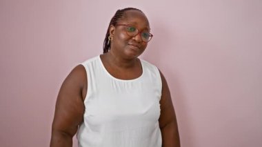 Kendinden emin Afrikalı Amerikalı kadın, neşeli bir şekilde merhaba diyor, pembe bir arka planda birini arıyor.