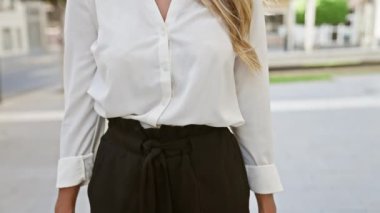 Çekici, genç bir yetişkin, güzel, sarışın bir kadın, sakin ve kolları çapraz duran şehir caddesinde, açık havada, bir portre