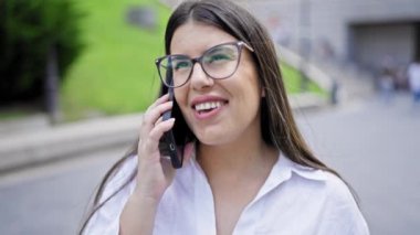 Genç ve güzel İspanyol kadın gülümsüyor. Madrid sokaklarında telefonda mutlu bir şekilde konuşuyor.