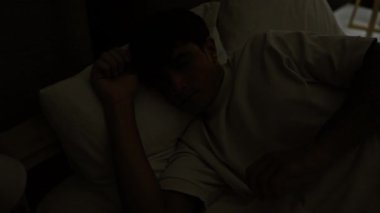 Mutlu İspanyol genç kollarını sabah yatağında esnetiyor, kendine güvenerek aydınlık bir yatak odasında uyanıyor.