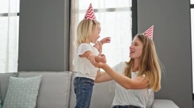 Oturma odasındaki kanepede otururken rahatça gülümseyen Kafkas anne ve kızı arasında samimi bir kucaklaşma..