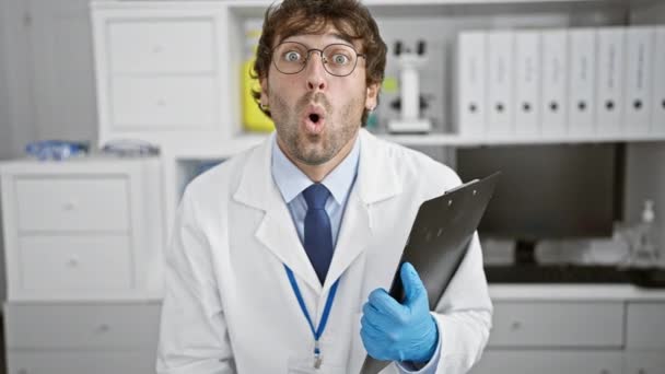 震惊的年轻科学家张开嘴 害怕的脸在实验室里难以置信 金发碧眼 满脸胡须的专业人士在他的研究地点惊讶不已 — 图库视频影像