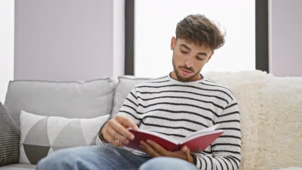 Jovem Árabe Homem Leitura Livro Sentado Sofá Casa — Vídeo de Stock