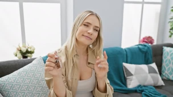 Podekscytowana Młoda Blondynka Siedząca Kanapie Nowym Domu Kluczami Ręku Gotuje — Wideo stockowe